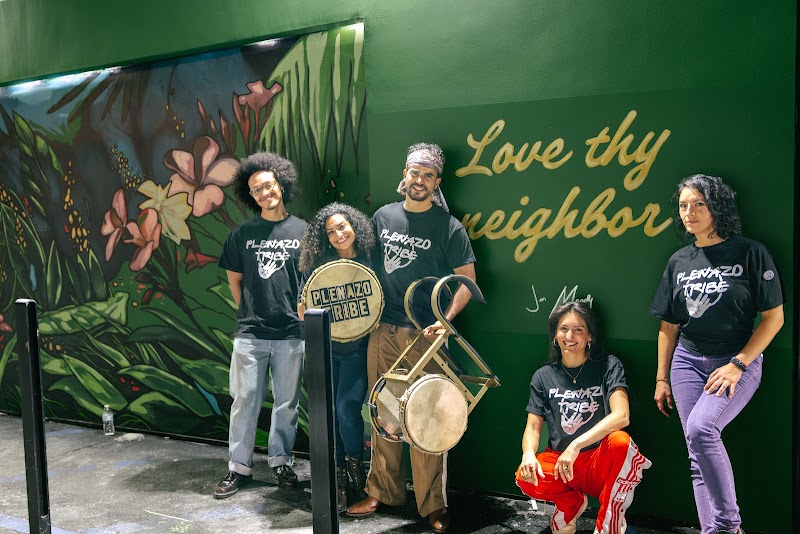 A group in front of the Love Thy Neighbor mural